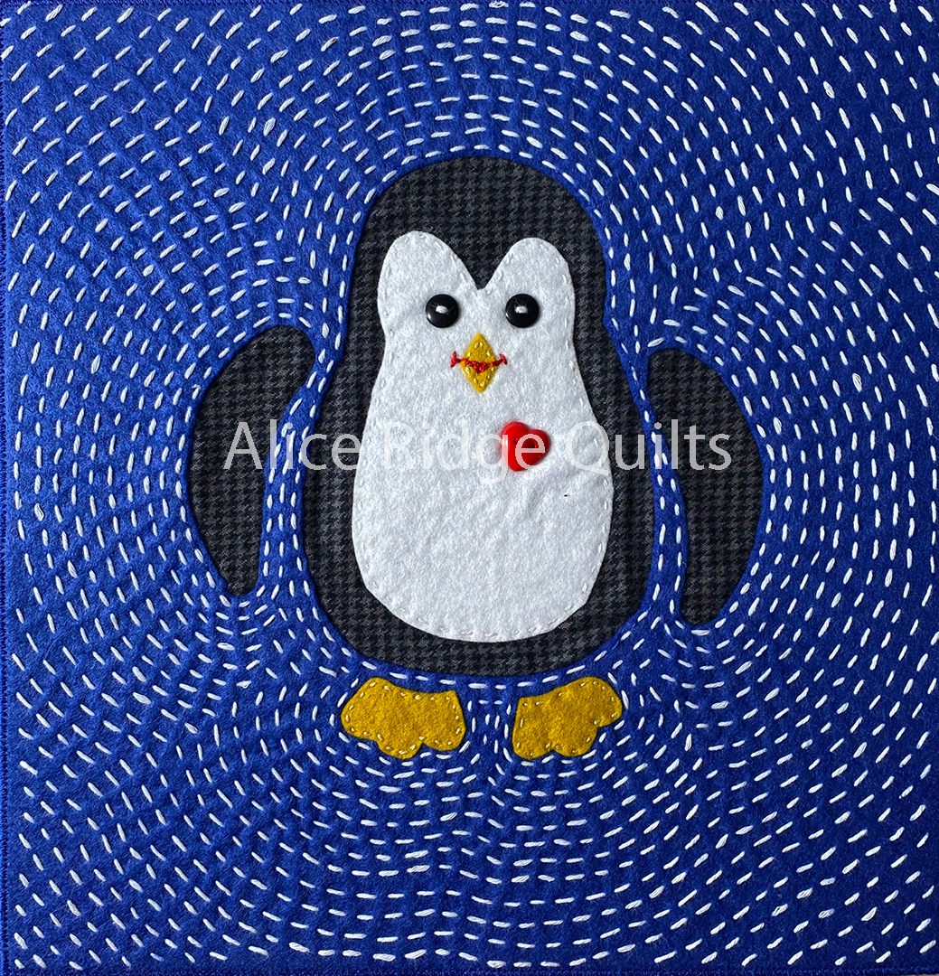 Hand-stitched Mock Mola quilt featuring a charming black and white penguin with a red heart button on a swirling blue and black stitched background.